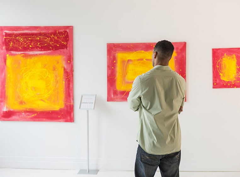 A man stares at three paintings hanging on a museum wall in Midtown Atlanta.