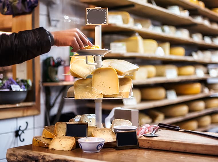 A hand reaching for a sample of cheese off of a tiered platter at Krog Street Market in Atlanta, Georgia.