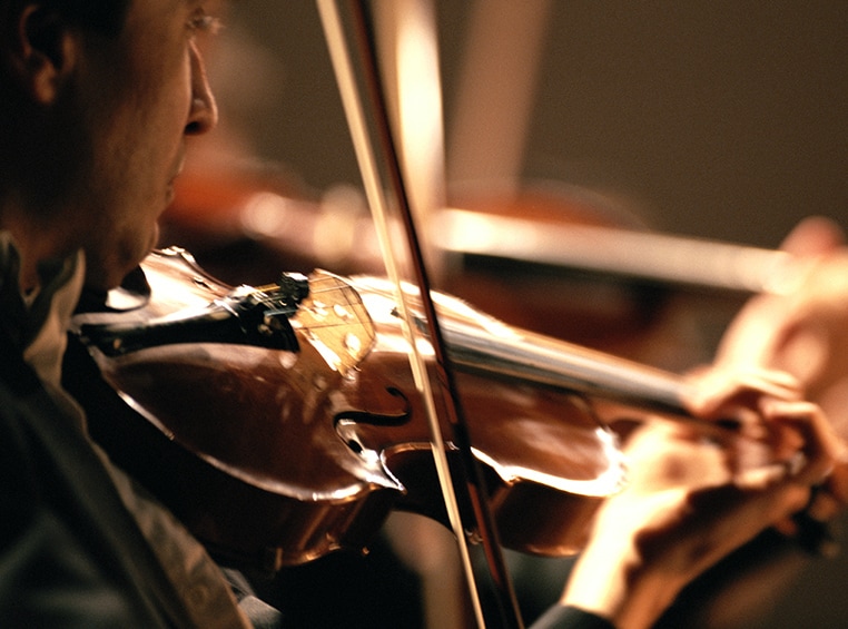 A close up of a man playing a violin. 