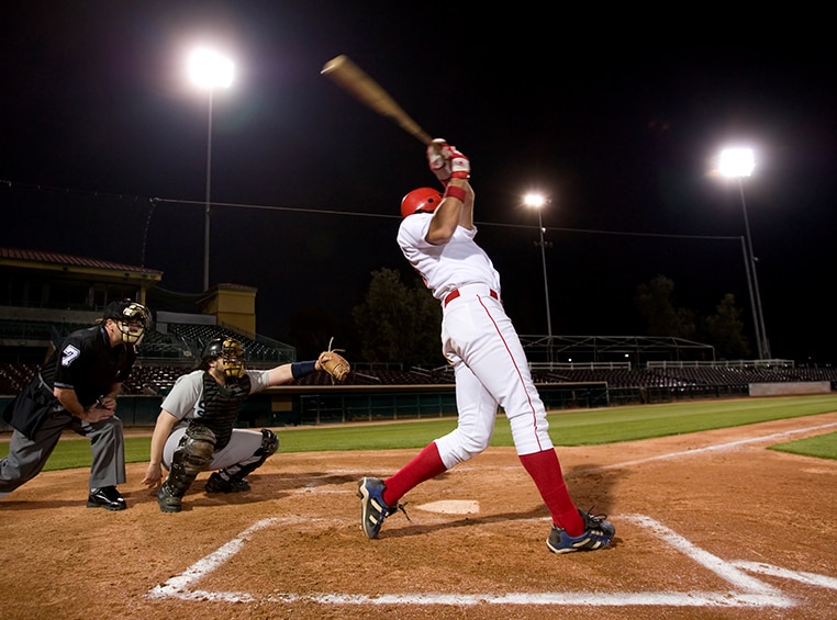An african american male baseball player is swinging his bat.