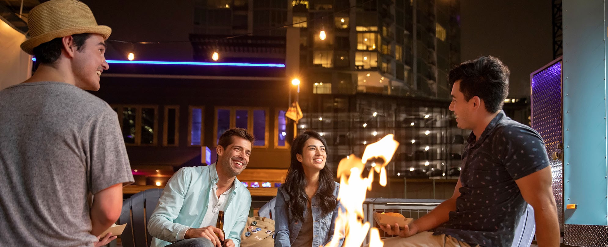 A group of friends sit in conversation around a fire on the rooftop deck of WorldMark Austin.