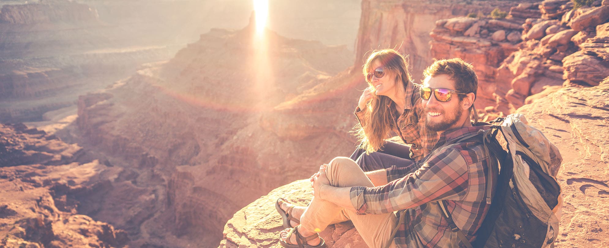 A couple, posing for a photo, on top of a large red rock formation, at Red Rock Wonderland.