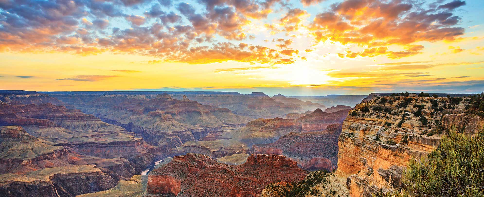 A vibrant yellow and orange sunset over the Grand Canyon in Arizona on a national park vacation
