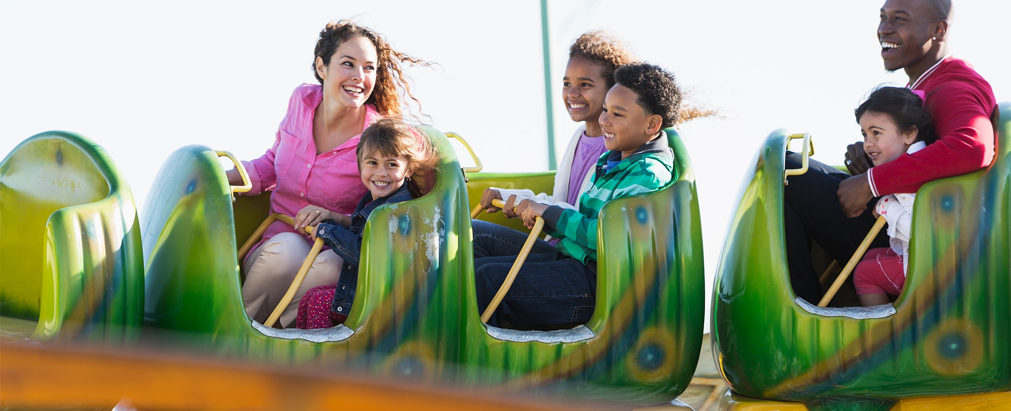 Kids and adults riding a children's rollercoaster at one of the Orlando theme parks.