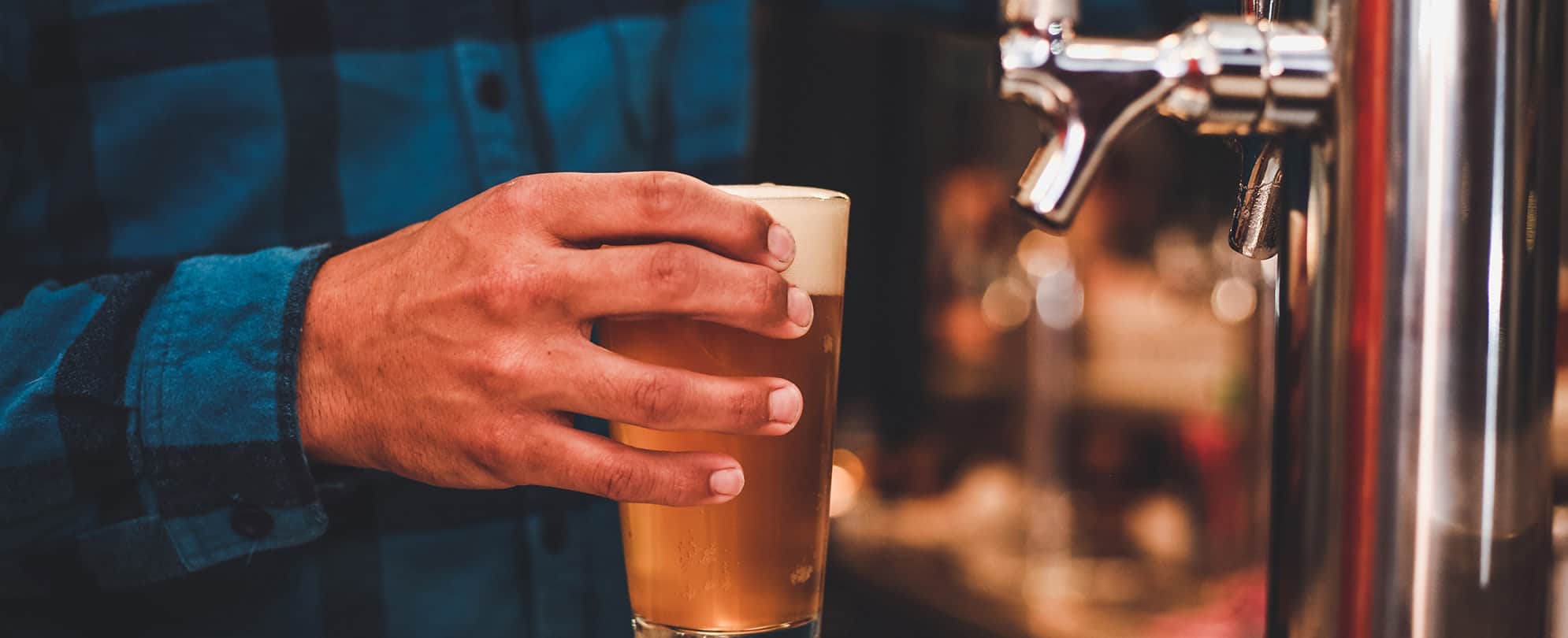 A hand holds a glass of beer at a brewery in Park City, Utah.