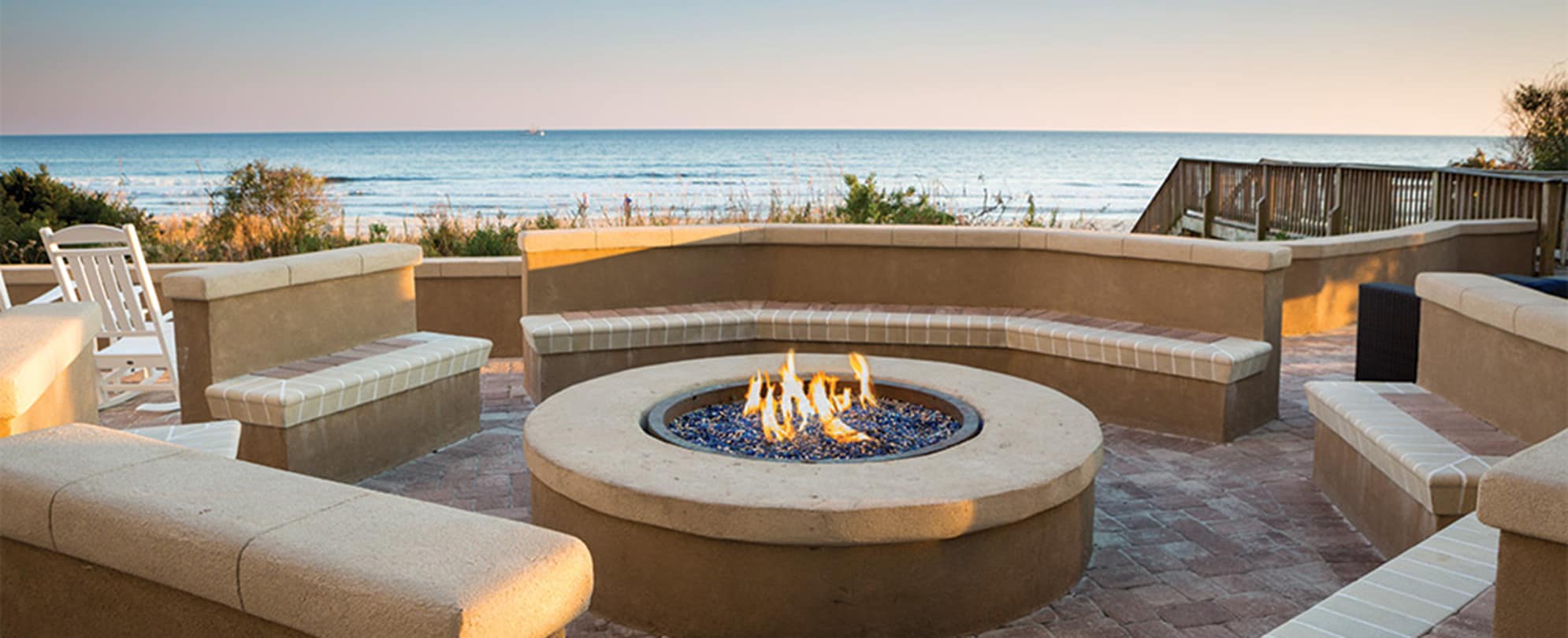 Wide view of an outdoor firepit by the beach.