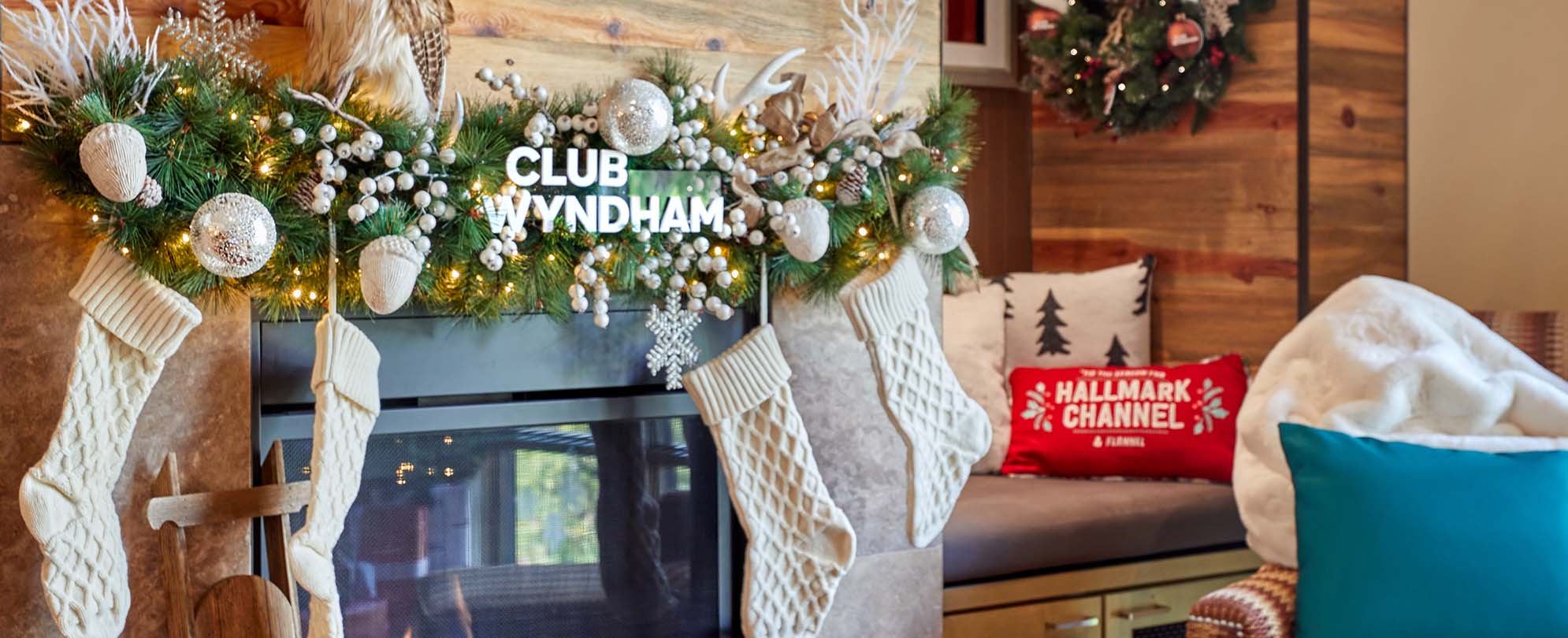 A fireplace decorated with Club Wyndham holiday garland and stockings inside a Hallmark Channel Countdown to Christmas Holiday suite at Club Wyndham Resort at Avon. 