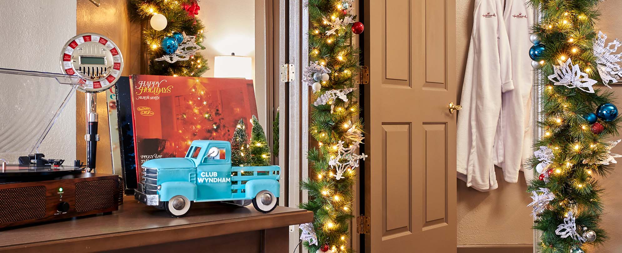 A record player, a Christmas record, and a charming blue toy truck with Christmas trees in the bed of the truck.