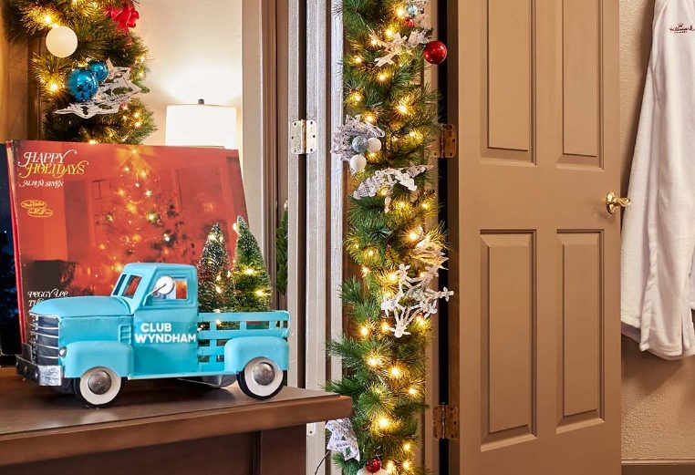 A record player, a Christmas record, and a charming blue toy truck with Christmas trees in the bed of the truck.
