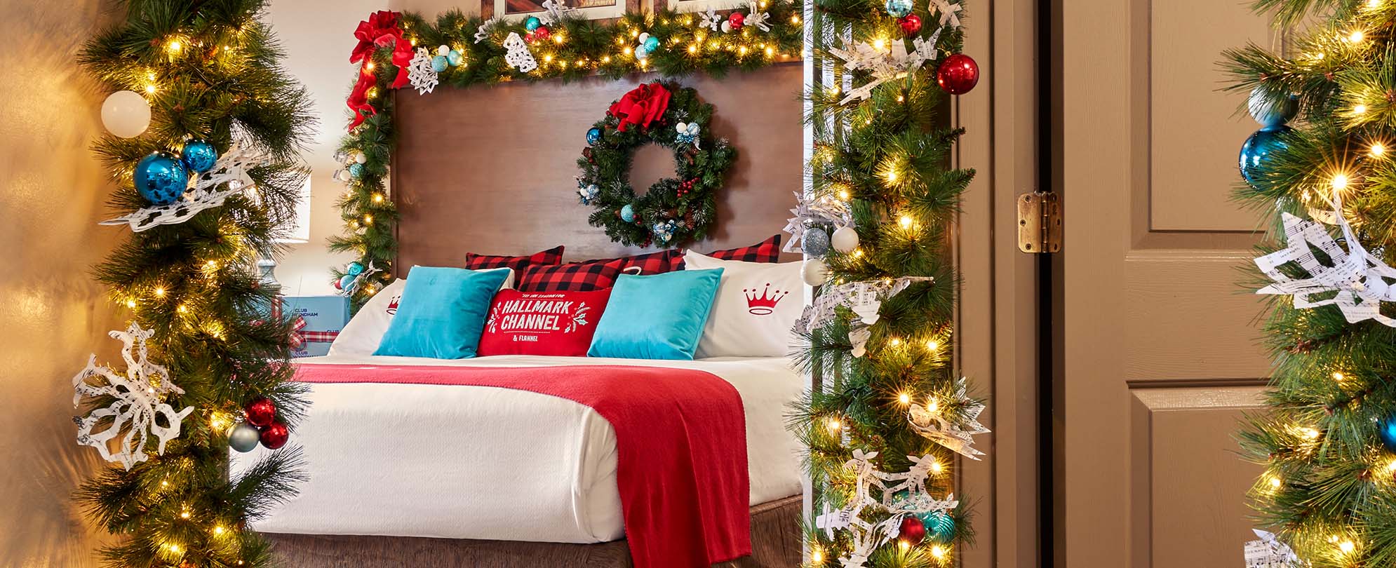 Christmas garland hanging from the doorway and bed frame of a king bed inside the Hallmark Channel Countdown to Christmas Holiday suite in Nashville, TN.