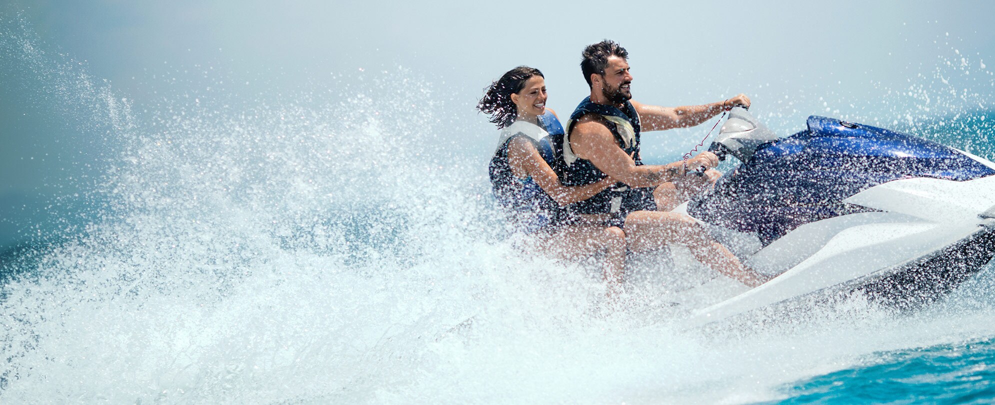 A man and a woman ride a jet ski on their Club Wyndham vacation.
