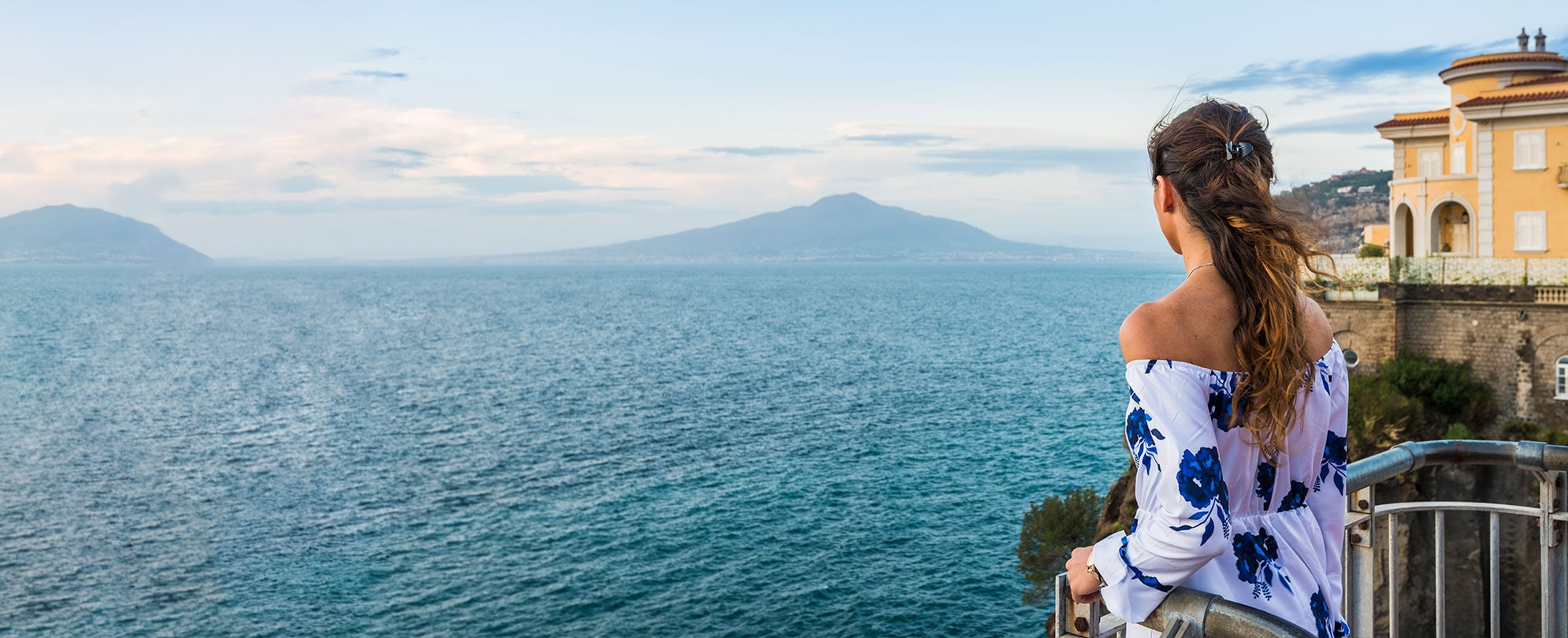 A woman looking out over the ocean and mountains in Sorrento, Italy.