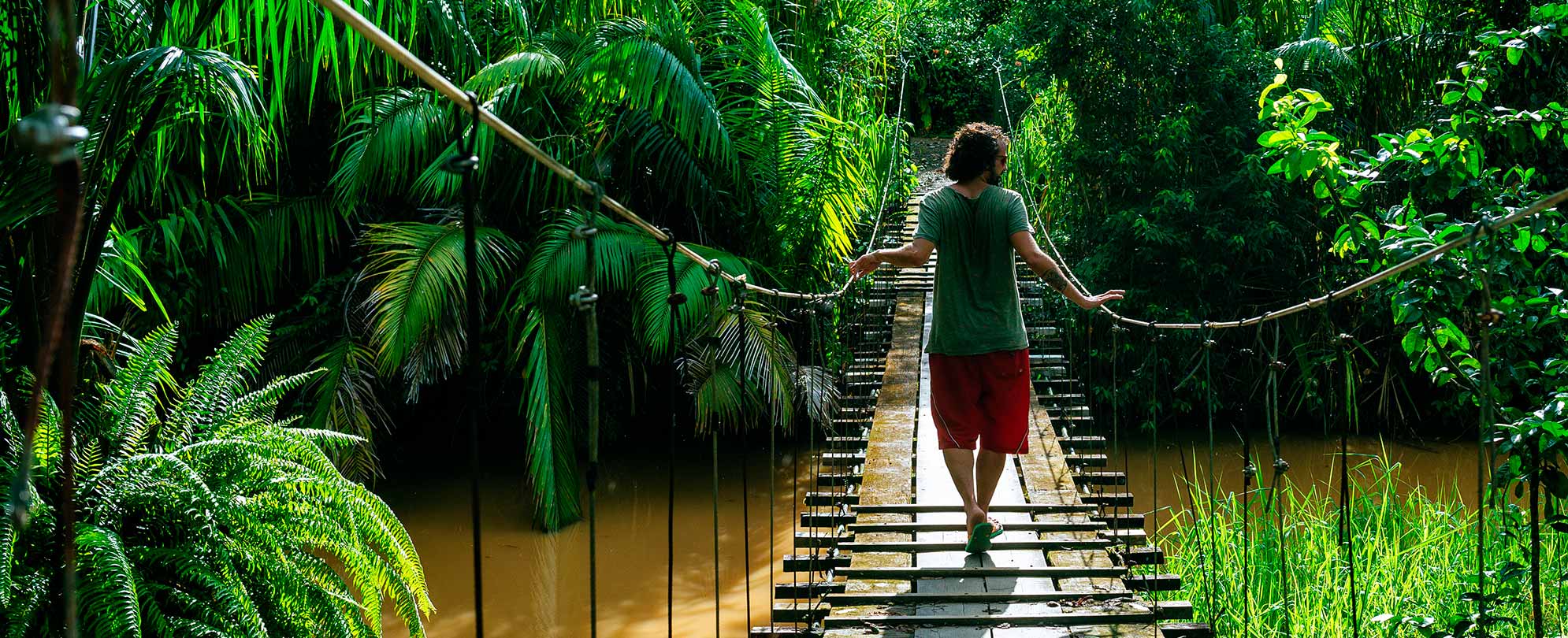A person walking across a small bridge surrounded by lush landscape in the Panama Canal with Club Wyndham.