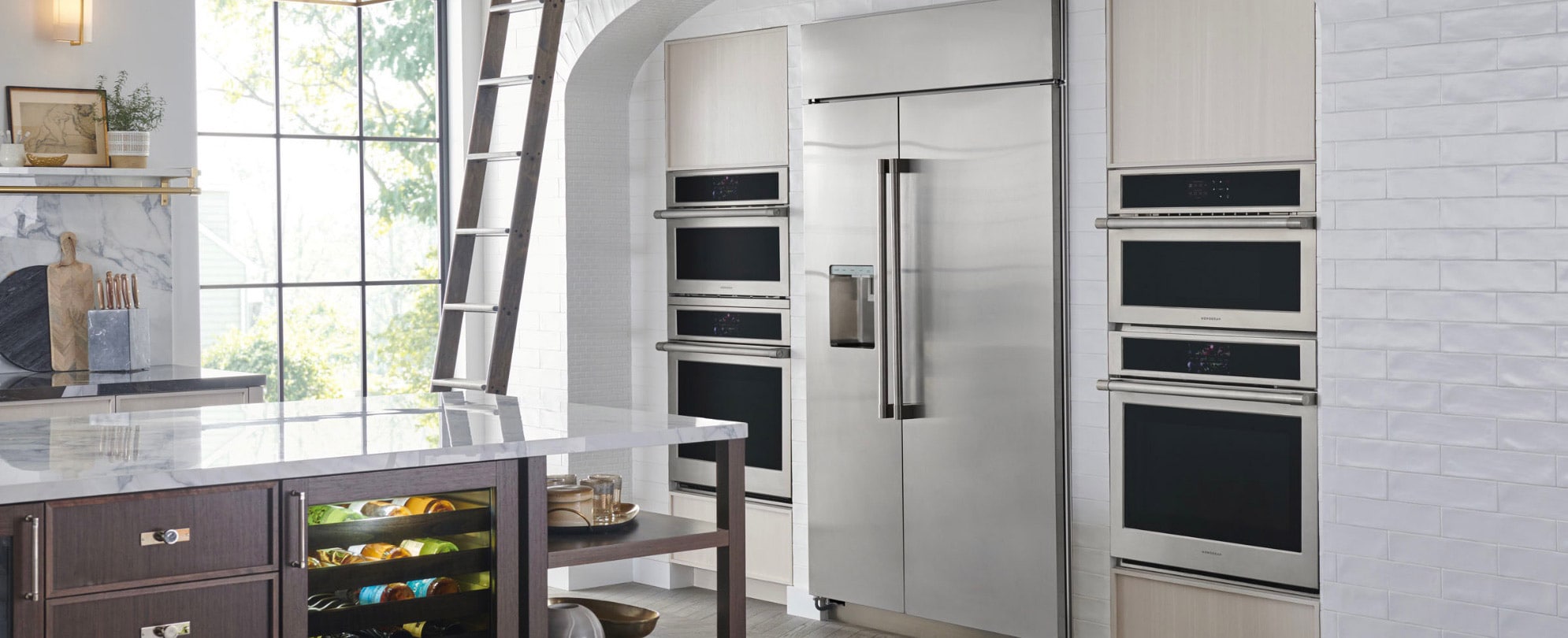 A contemporary kitchen showcasing a built-in refrigerator and four ovens from GE Appliances. 