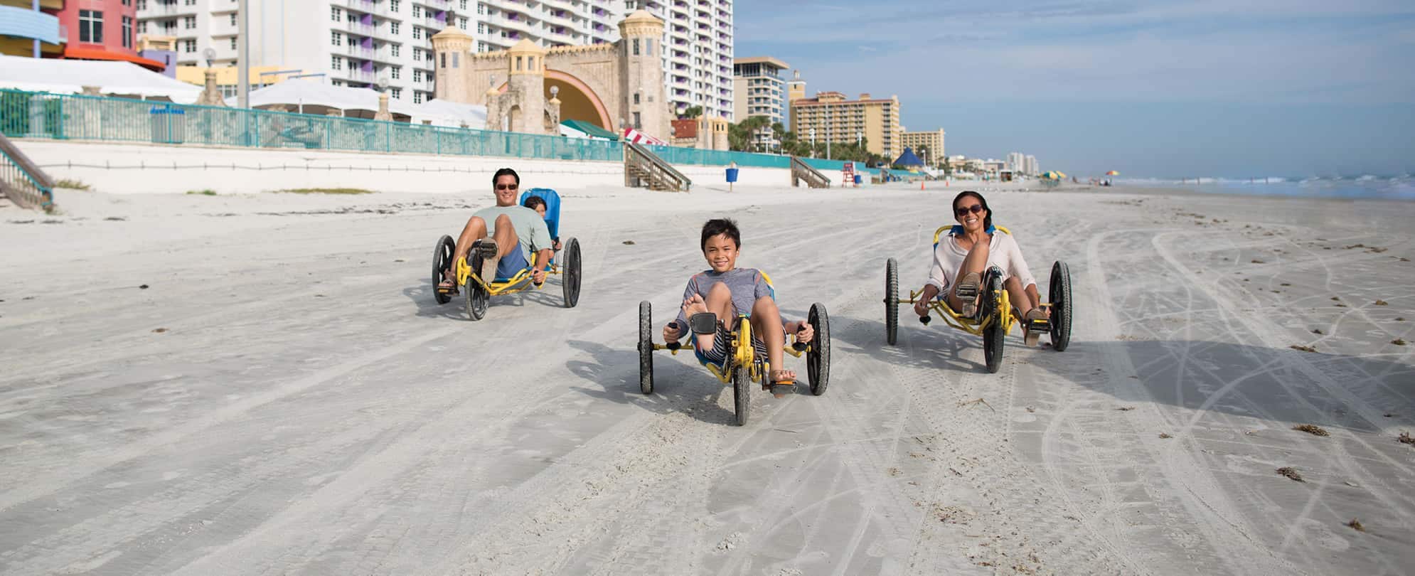 Family of four riding yellow tricycles on the beach 