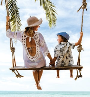 A mother and her son, sitting on a beach swing overlooking the ocean.