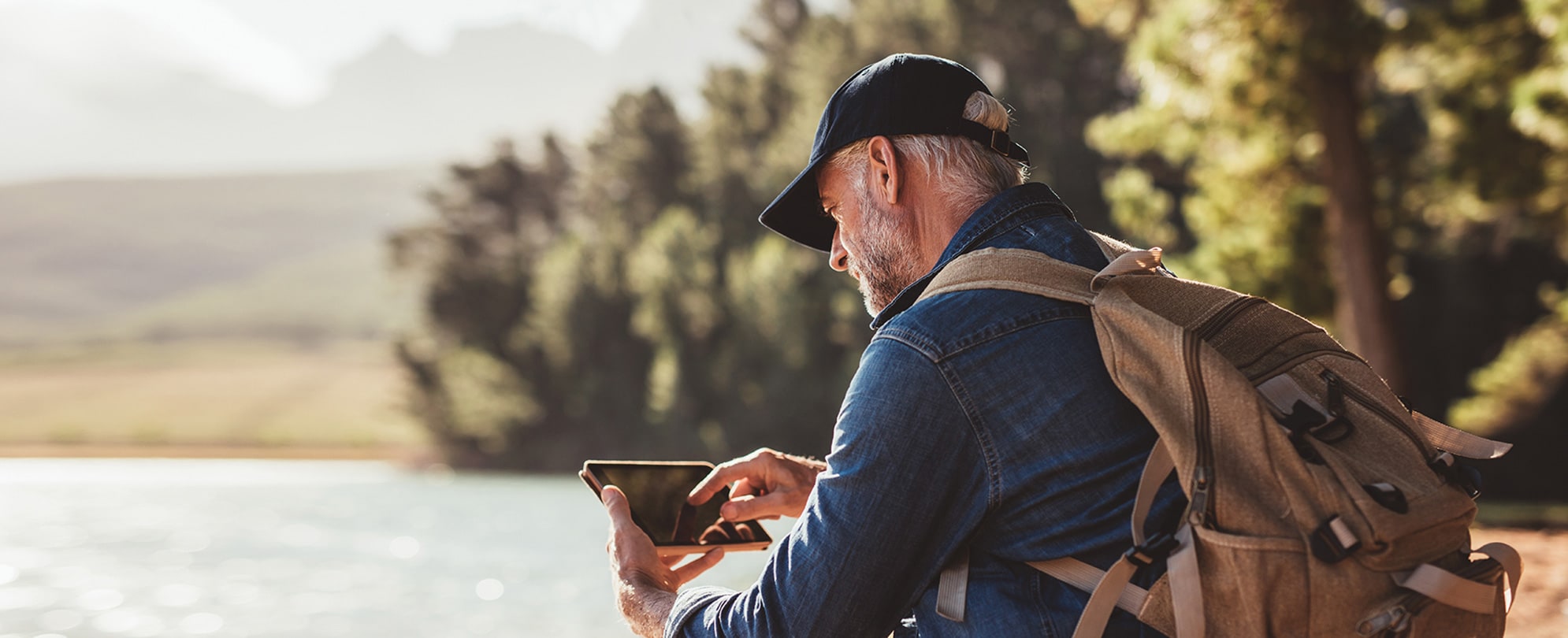 Man on a nature hike takes a break to check his smartphone.