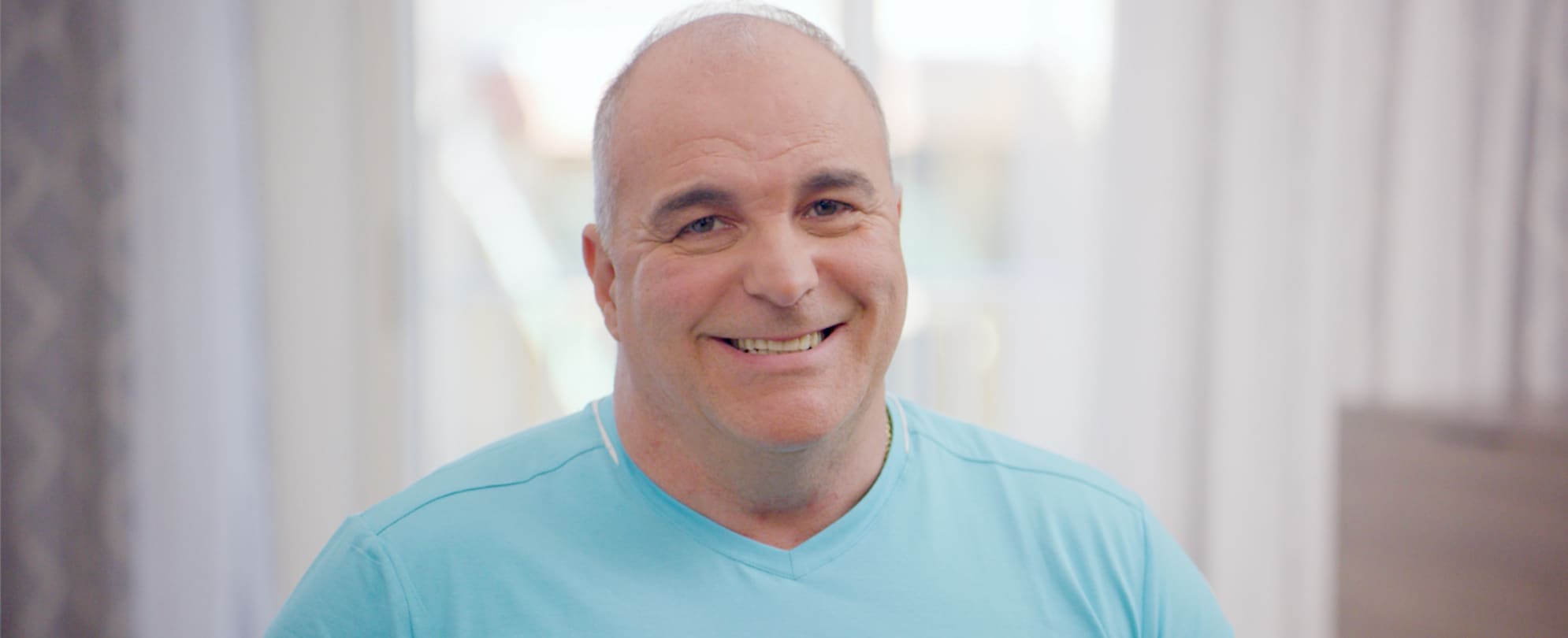 A timeshare owner wearing a bright blue t-shirt smiling directly into the camera