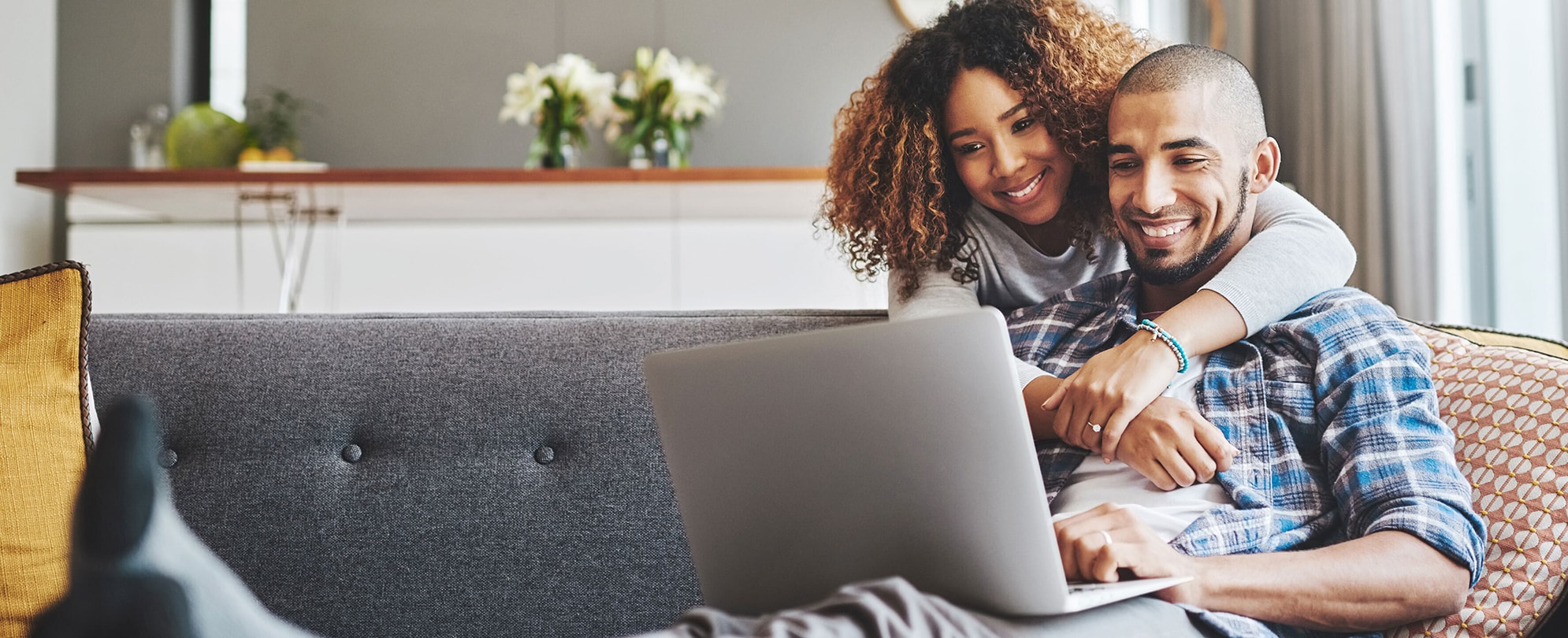 Happy couple on the couch with a laptop excited to read the latest Club Wyndham Resort News article