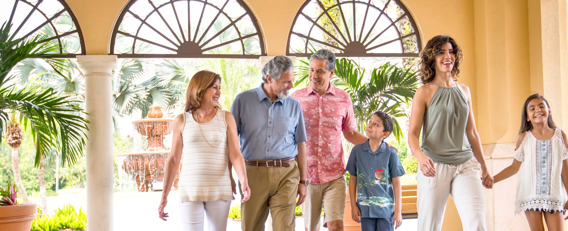 A happy family of six, walking side by side through a resort lobby. 
