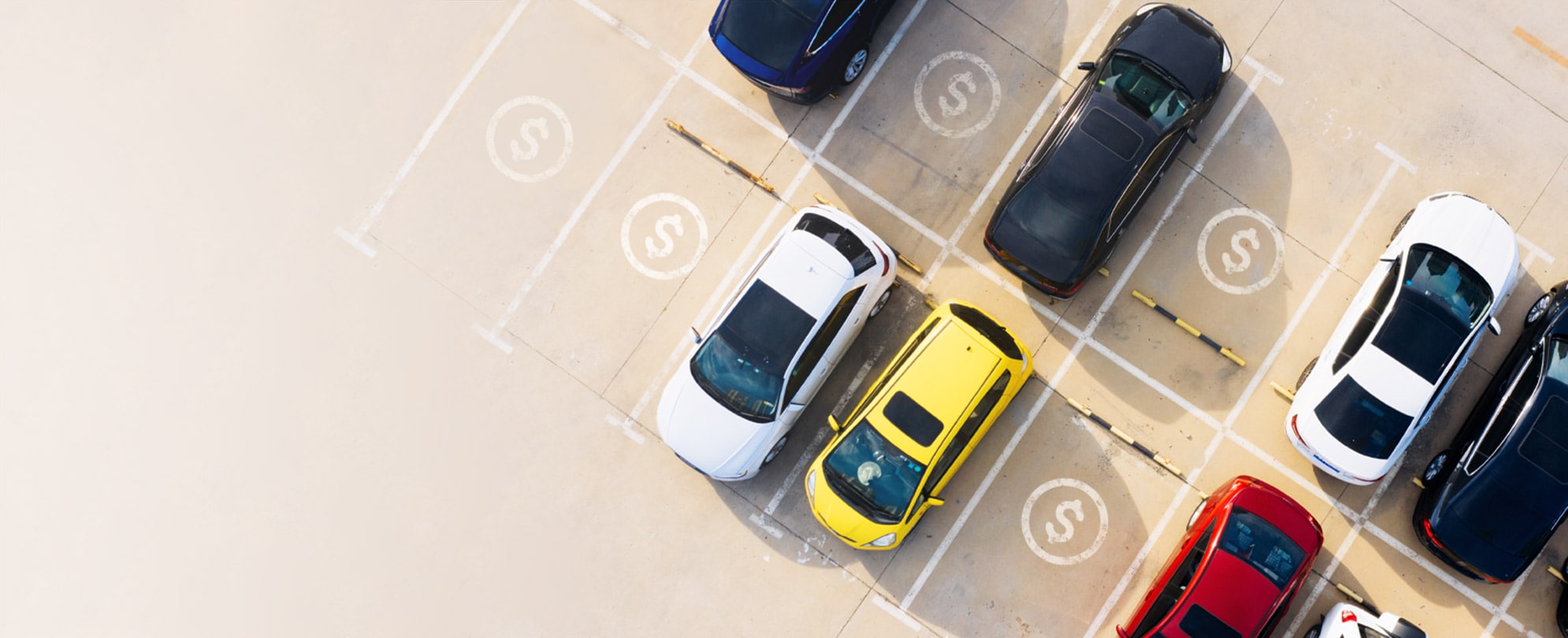 Overhead view of a parking lot with cars in some spaces, while empty spaces are marked with dollar signs.
