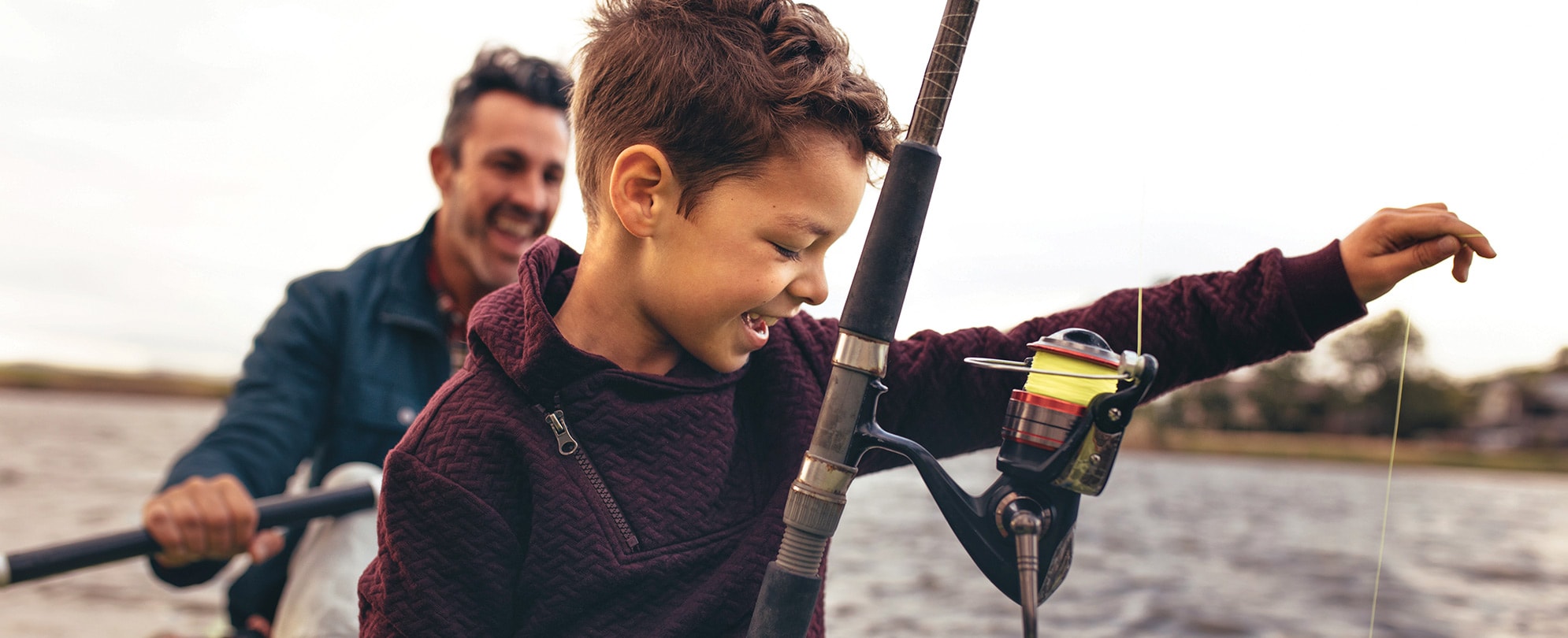 A smiling dad and son fishing on a kayak.