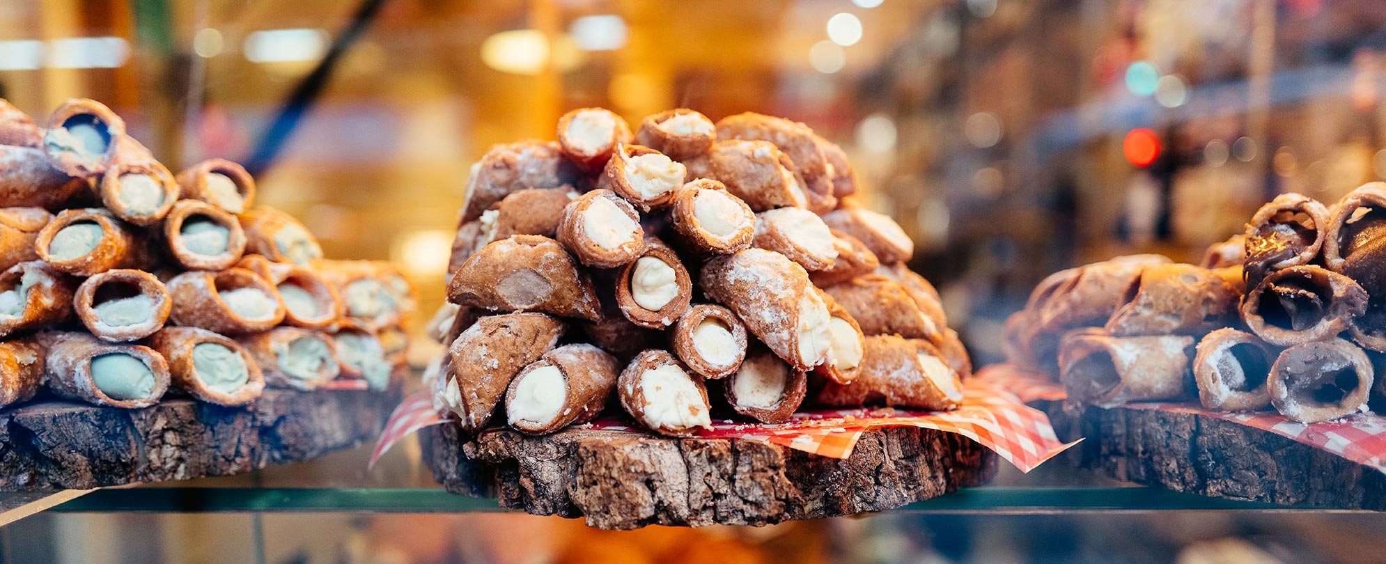 Cannoli stacked on three natural wood platters