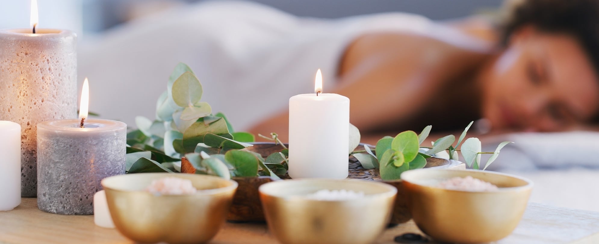 A spa guest lying on a massage table in a room with lit candles