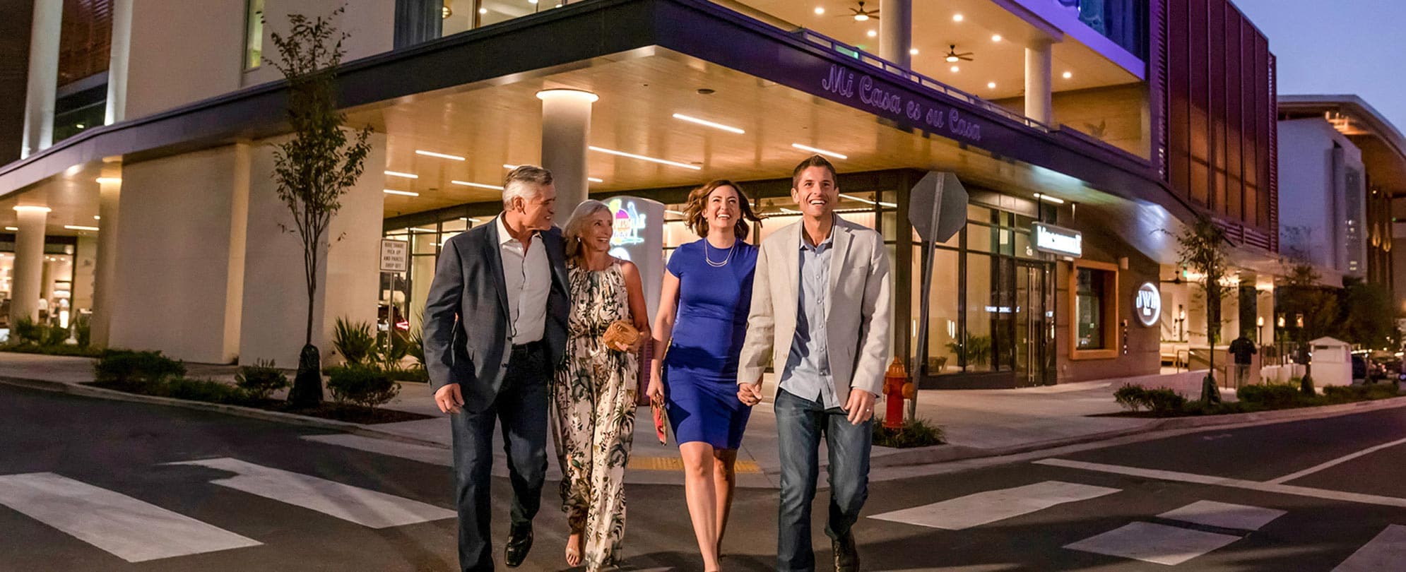 Four smiling adults wearing evening attire and walking outside the Margaritaville Hotel in Nashville, Tennessee
