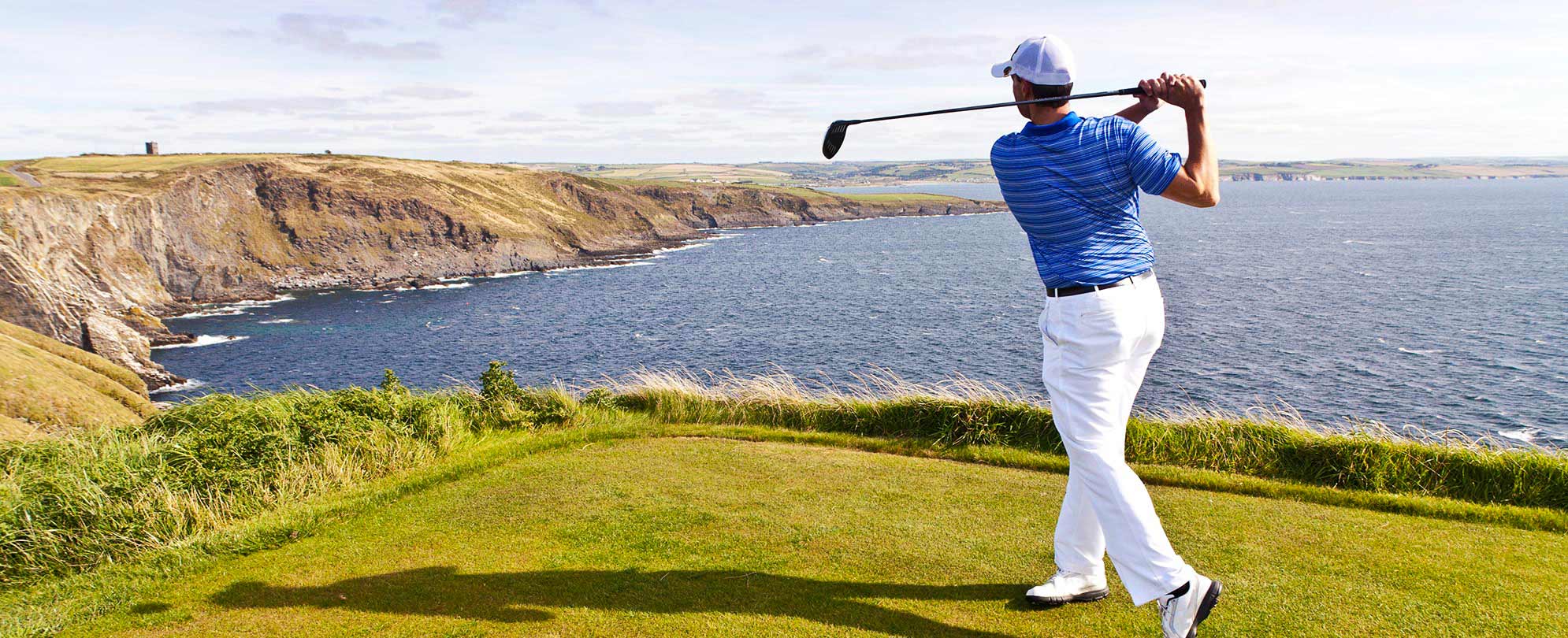 A golfer posing on a clifftop golf course overlooking the water