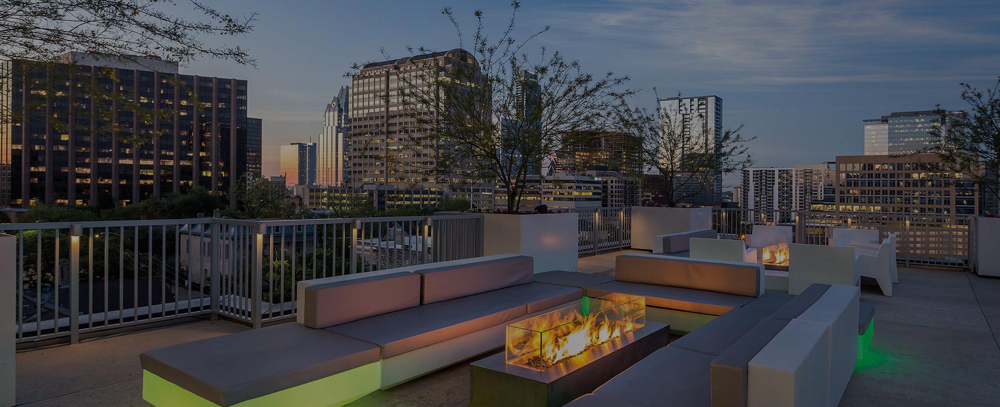 A rooftop lounge with couches and glass fireplaces at Club Wyndham Austin, the downtown skyline in the background.