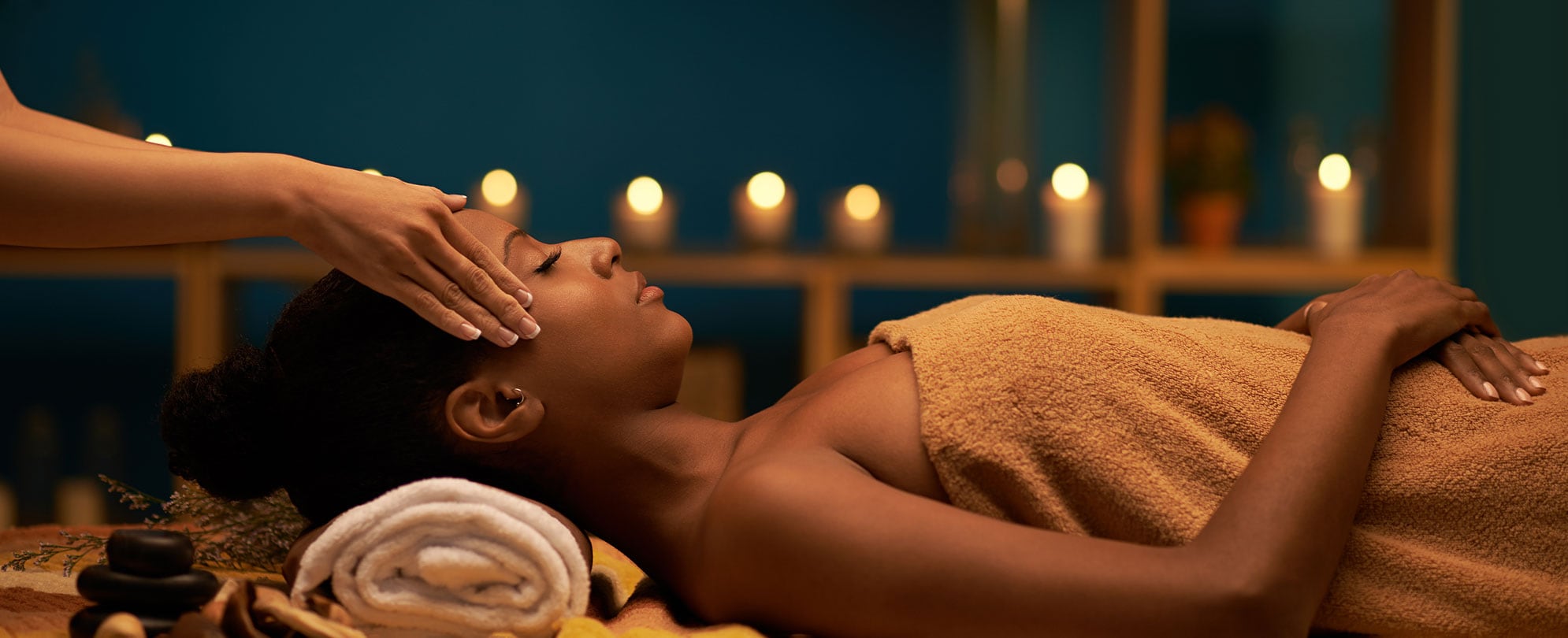 A woman receiving a massage and enjoying aroma therapy in dimly lit spa