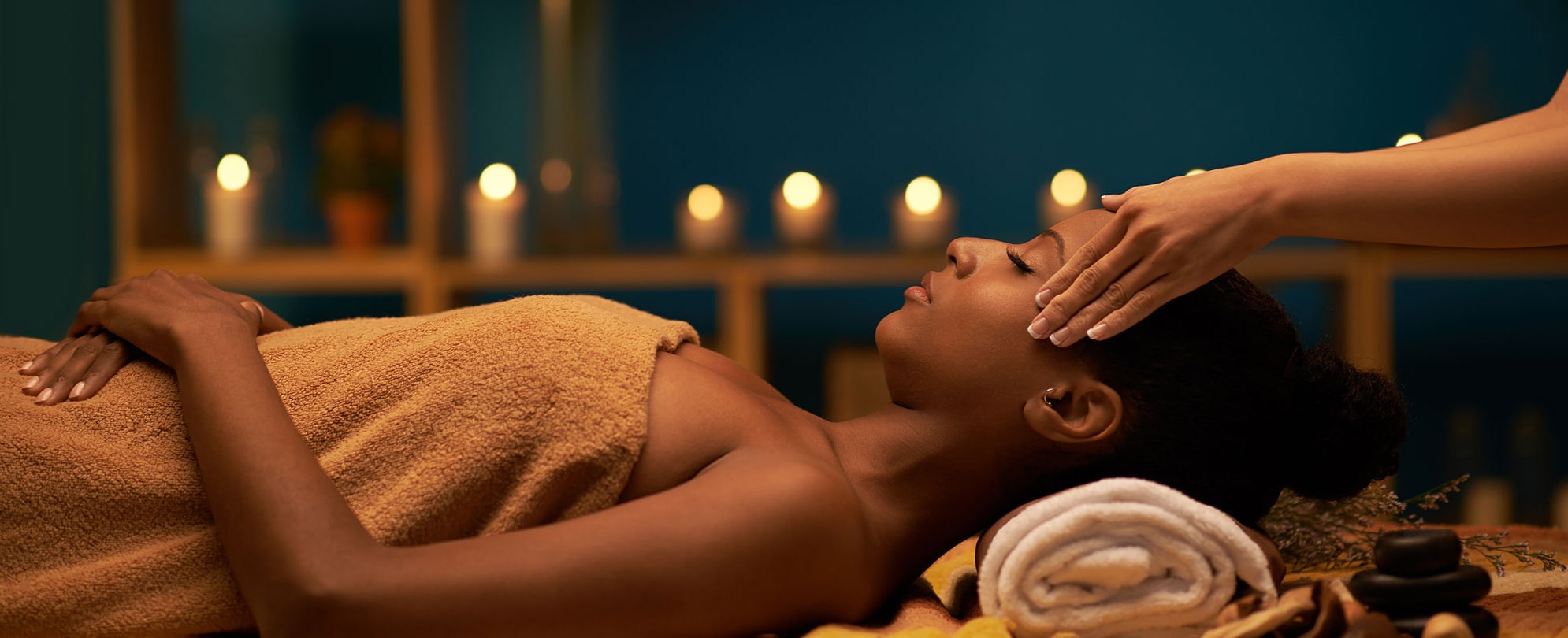 A woman receiving a massage and enjoying aroma therapy in dimly lit spa