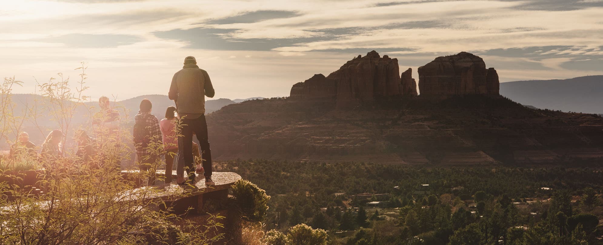 A father and his kids look out over the red rocks during a hike in Sedona, Arizona