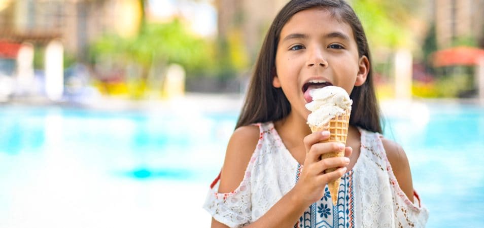 A young girl licks a vanilla ice cream waffle cone by the pool at a Club Wyndham resort