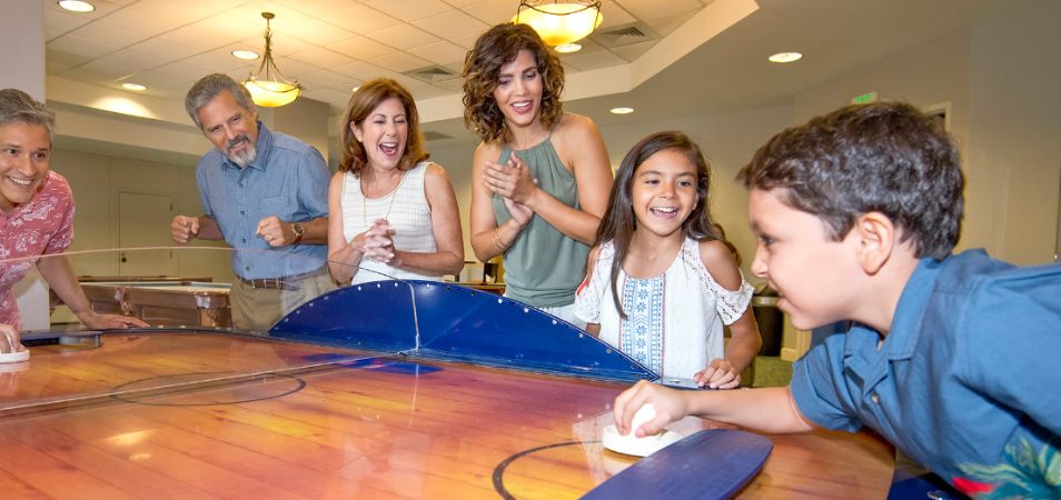 A family cheers on a young boy playing air hockey at a Club Wyndham resort.