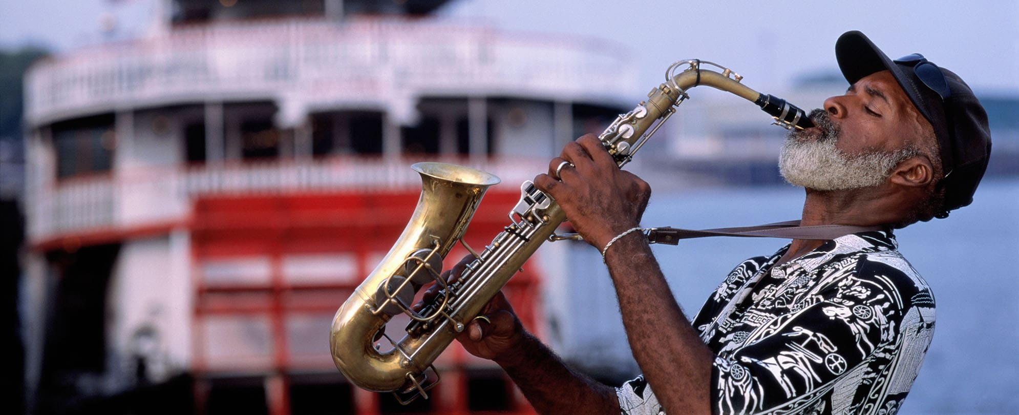 A man plays the saxophone in front of a steamboat cruise in New Orleans, Louisiana