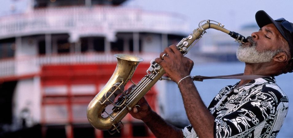 A man plays the saxophone in front of a steamboat cruise in New Orleans, Louisiana