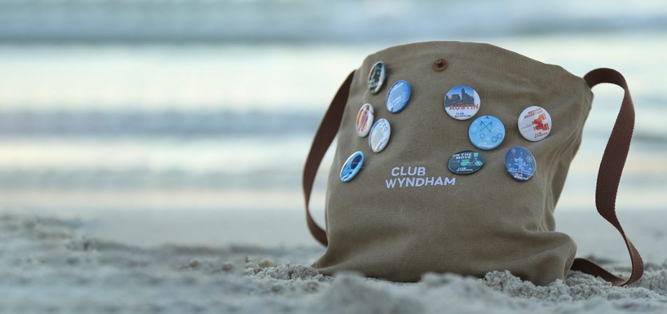 A club Wyndham canvas bag with ten pins is in the sand on a beach.