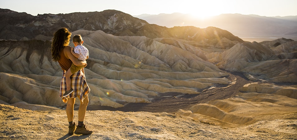 A woman holds a little boy as they both look over scenic desert hills.