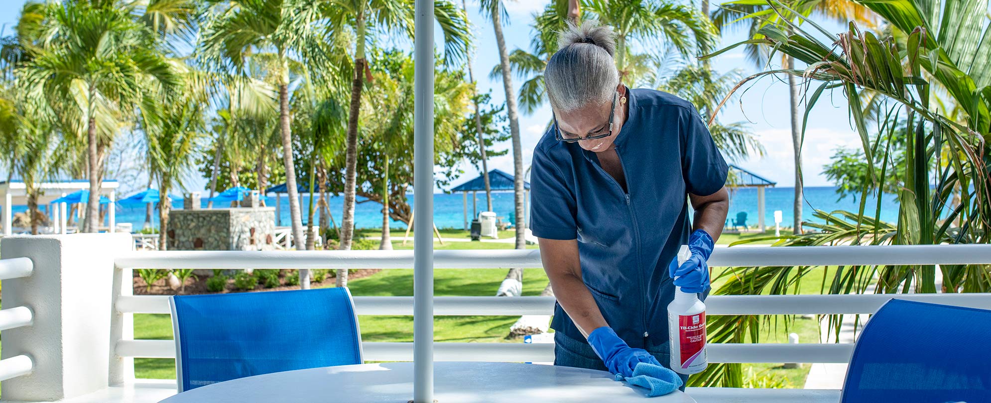 A housekeeper is cleaning the outdoor seating area at a Club Wyndham resort.