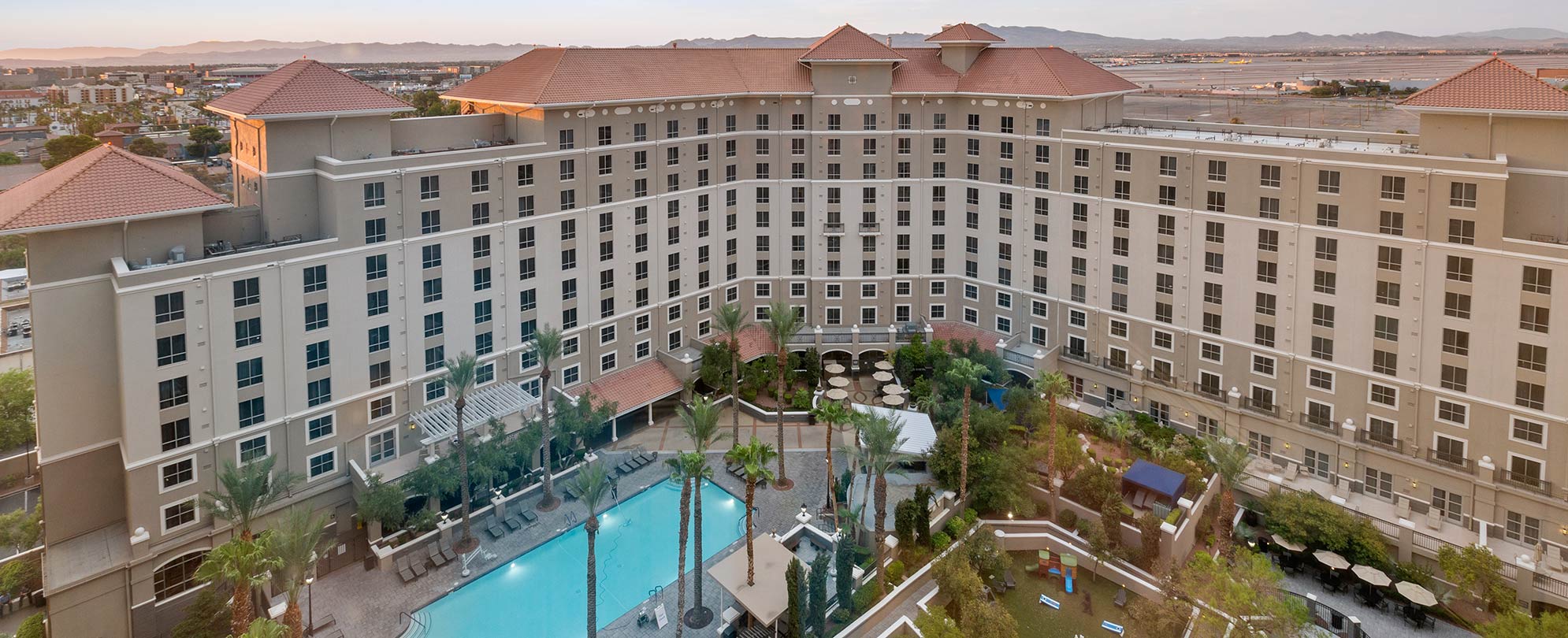 An outdoor pool surrounded by palm trees in front of Club Wyndham Grand Desert, a timeshare resort in Las Vegas, Nevada.