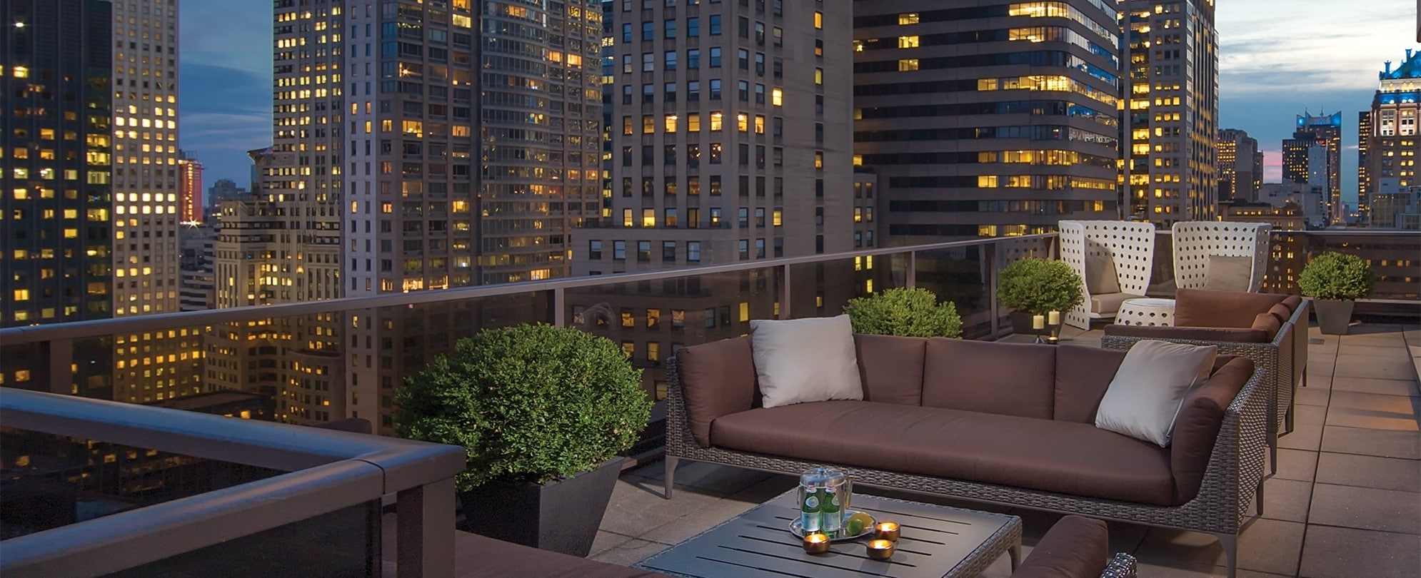 The rooftop patio at Club Wyndham Midtown 45, a timeshare resort in New York City, overlooking skyscrapers lit up at night.