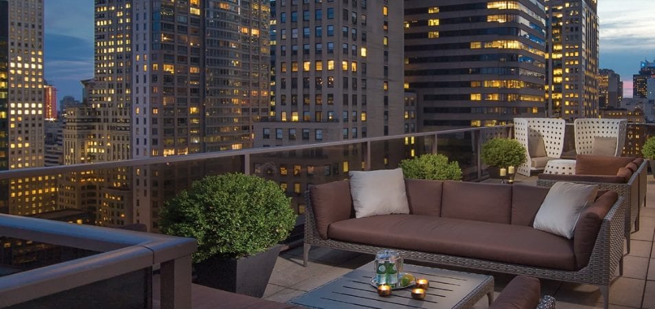 The rooftop patio at Club Wyndham Midtown 45, a timeshare resort in New York City, overlooking skyscrapers lit up at night.