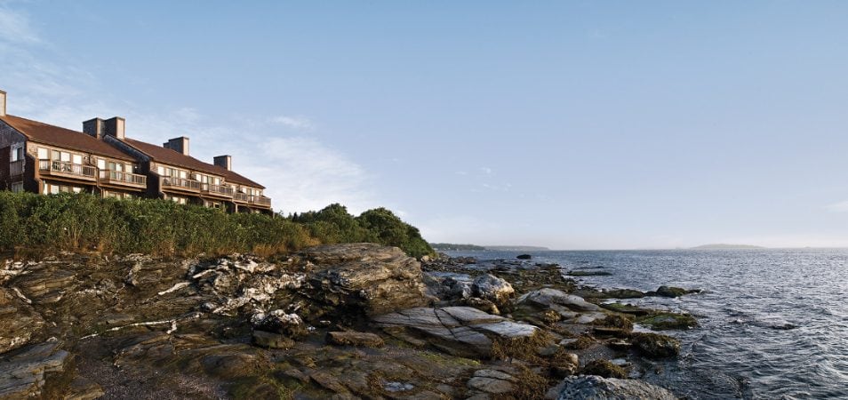 The exterior of Club Wyndham Newport Overlook, a timeshare resort in Newport, RI on a rocky shoreline.