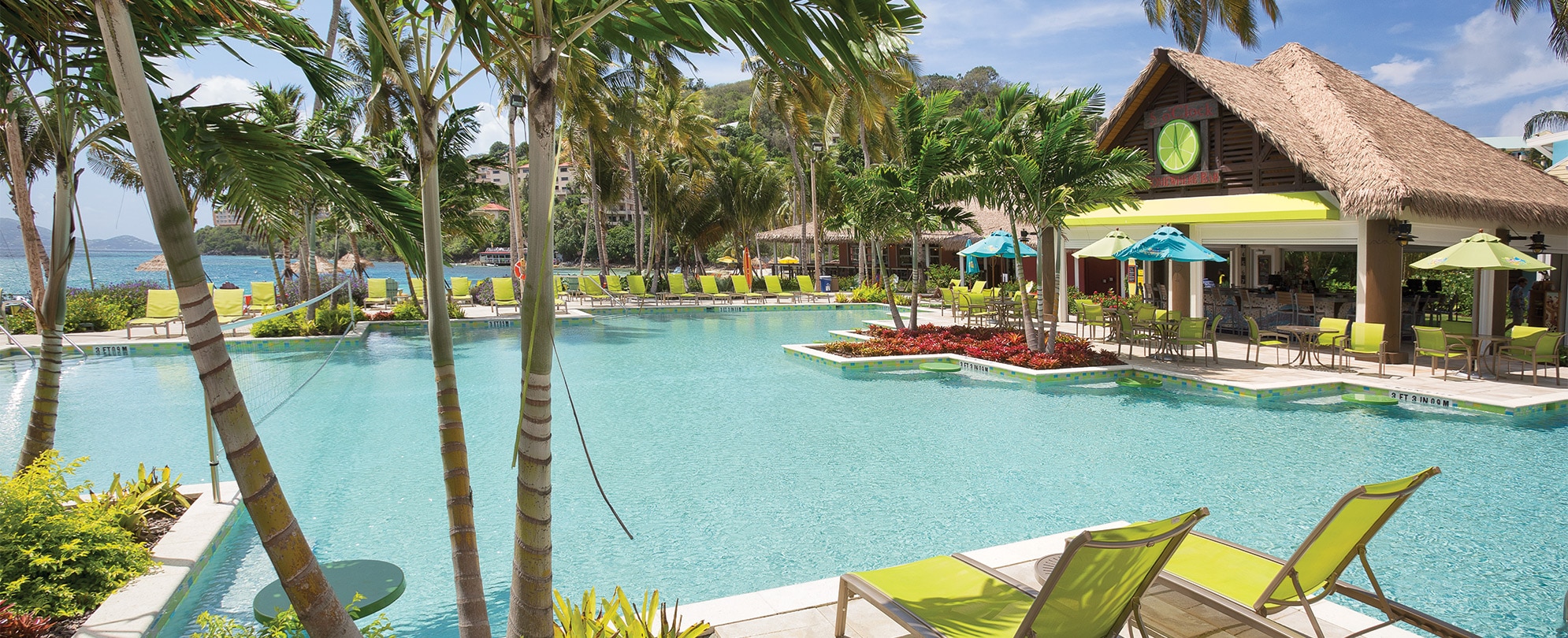Bright green pool chairs and palms surround the pool and tiki bar of Margaritaville Vacation Club by Wyndham - St. Thomas.