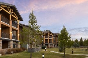The exterior of a resort with trees and cloudy skies in Montana at the WorldMark West Yellowstone.