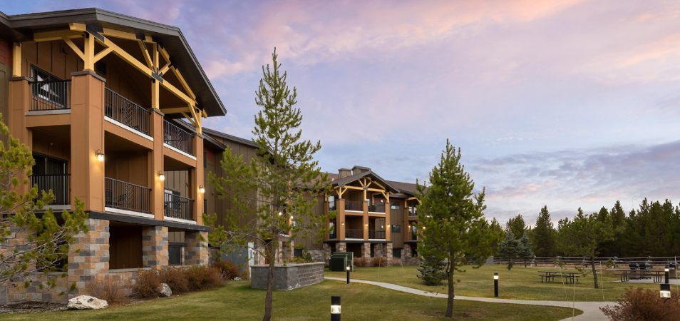 The exterior of a resort with trees and cloudy skies in Montana at the WorldMark West Yellowstone.