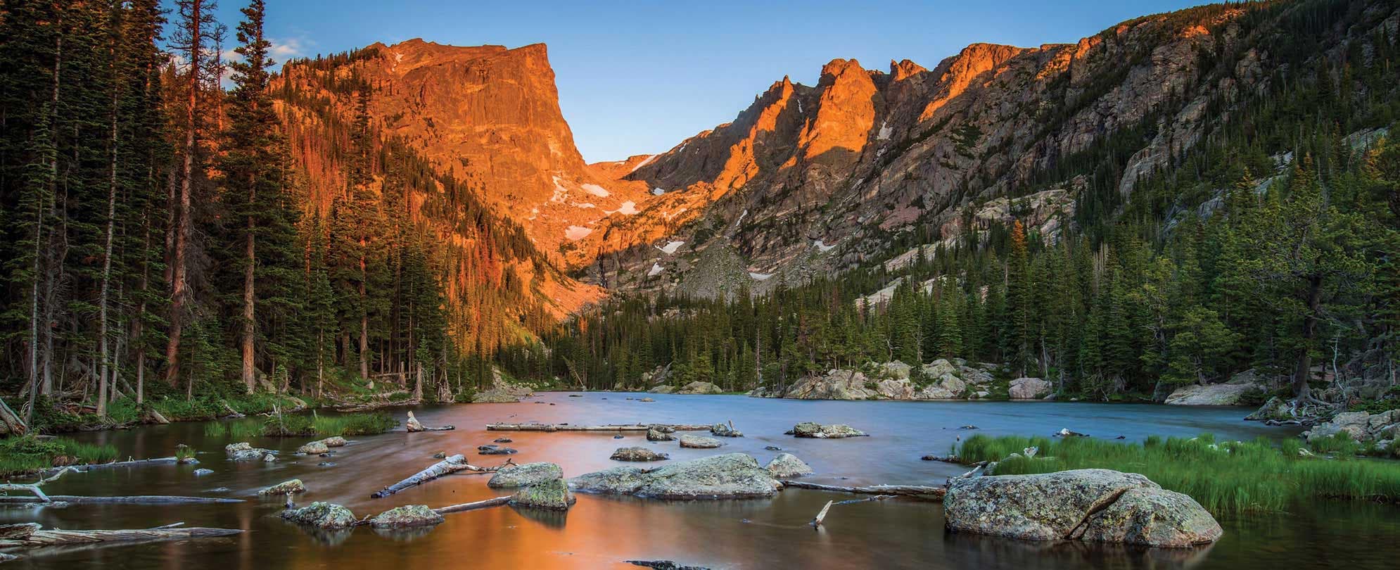 Mountains behind a rocky lake during golden hour at Rocky Mountain National Park in Colorado.