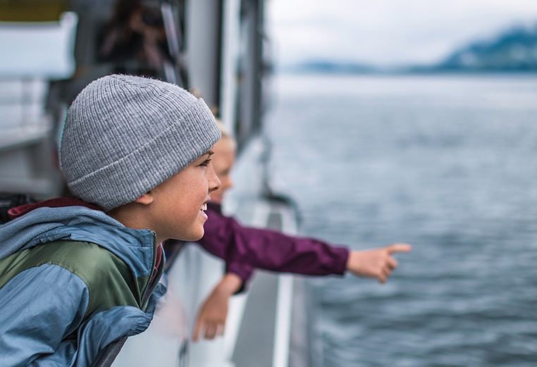 Three kids looking out into the ocean from a cruise ship in Alaska.